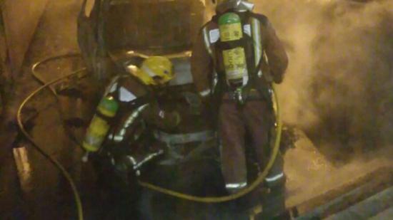 Els bombers en el moment que apagaven les flames que van calcinar totalment el cotxe. Foto:BOMBERS